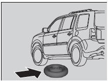 9. Place the compact spare tire (wheel side up) under the vehicle body, near